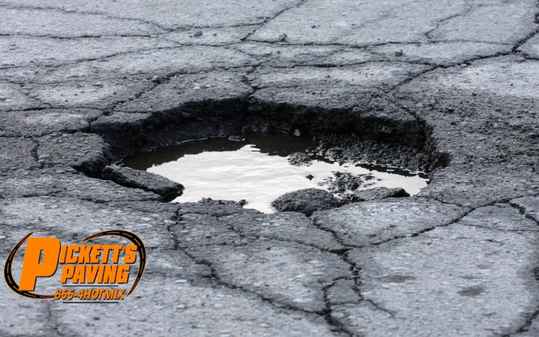 A pothole in the road filled with rain water with the "Pickett's Paving" logo in bottom left corner.